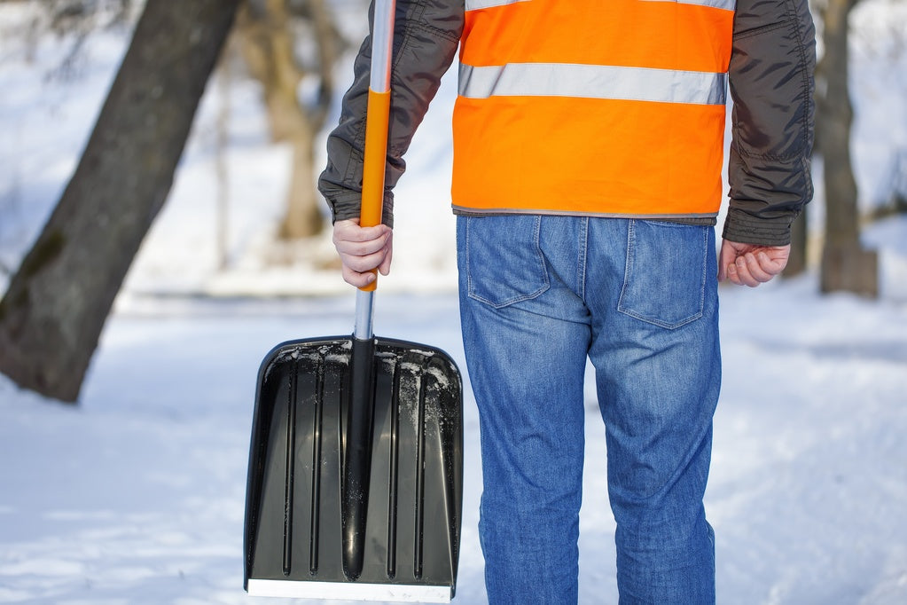 Man in a bright orange jacket holding a shovel