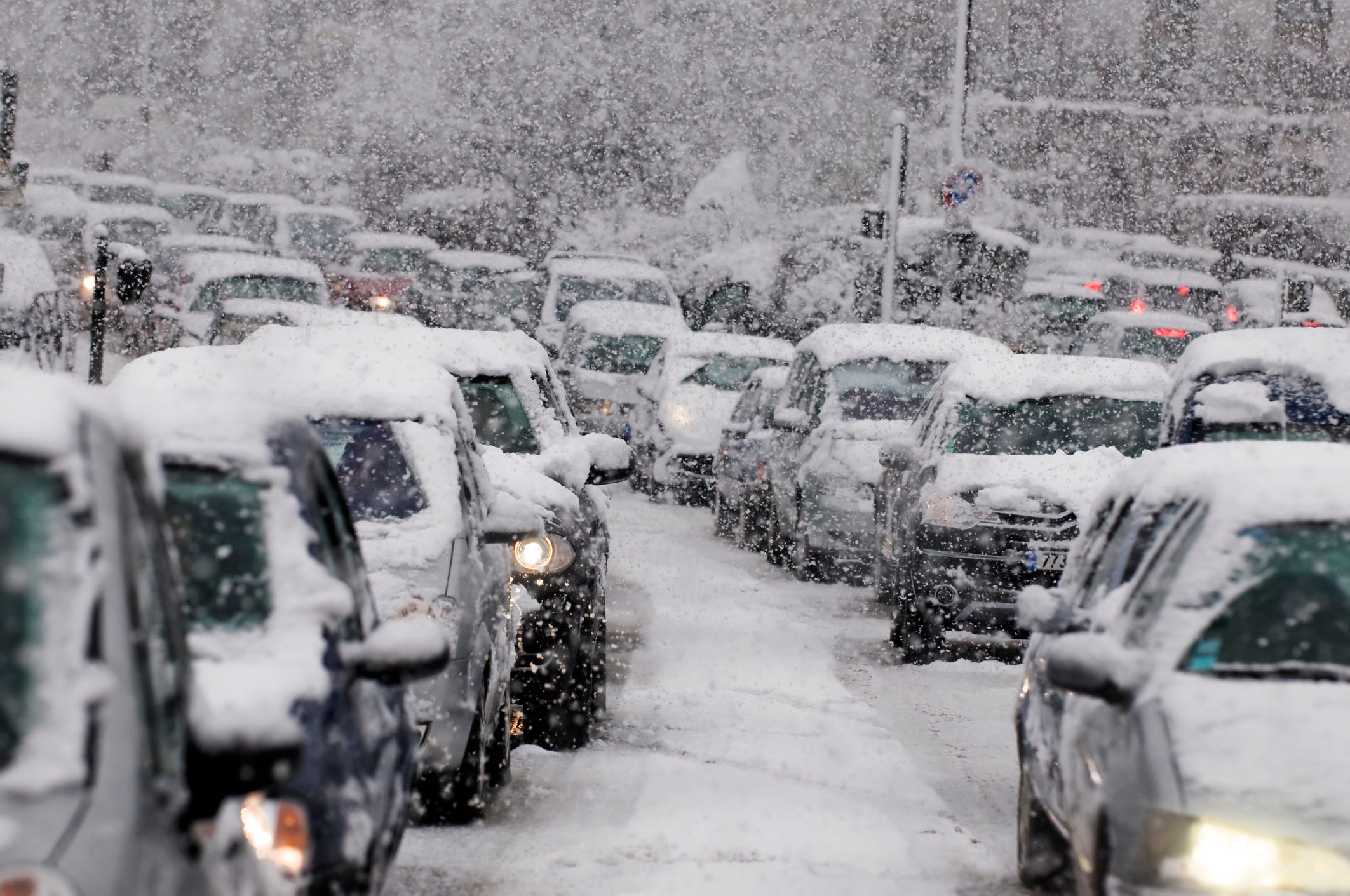 A line of cars are blanketed in heavy snow