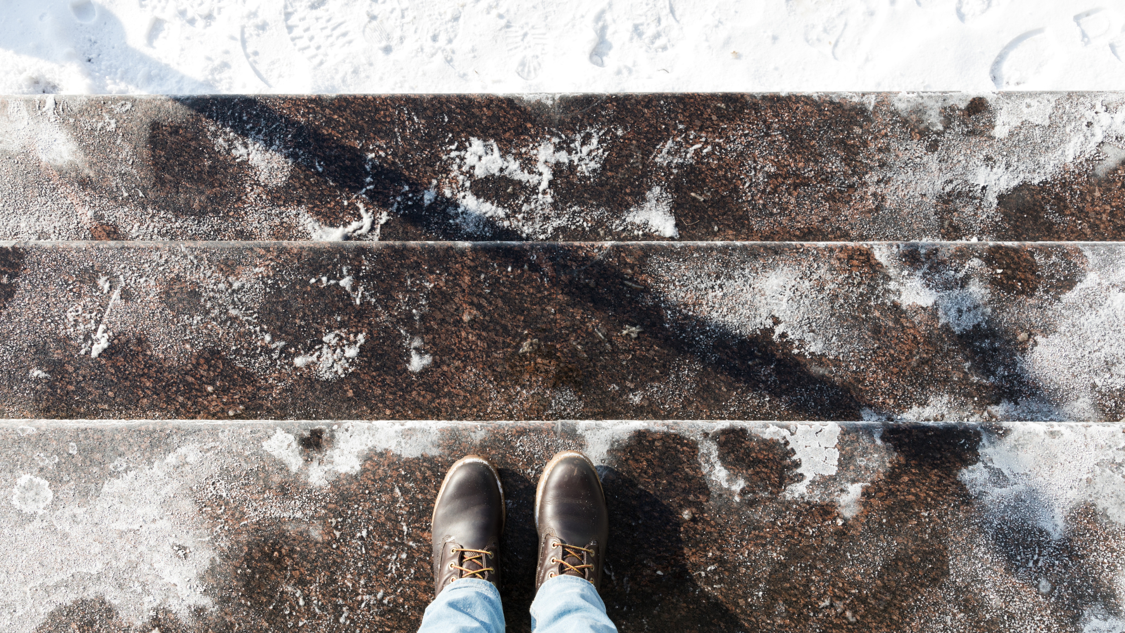 A person is standing on steps that are covered in calcium chloride and bits of ice