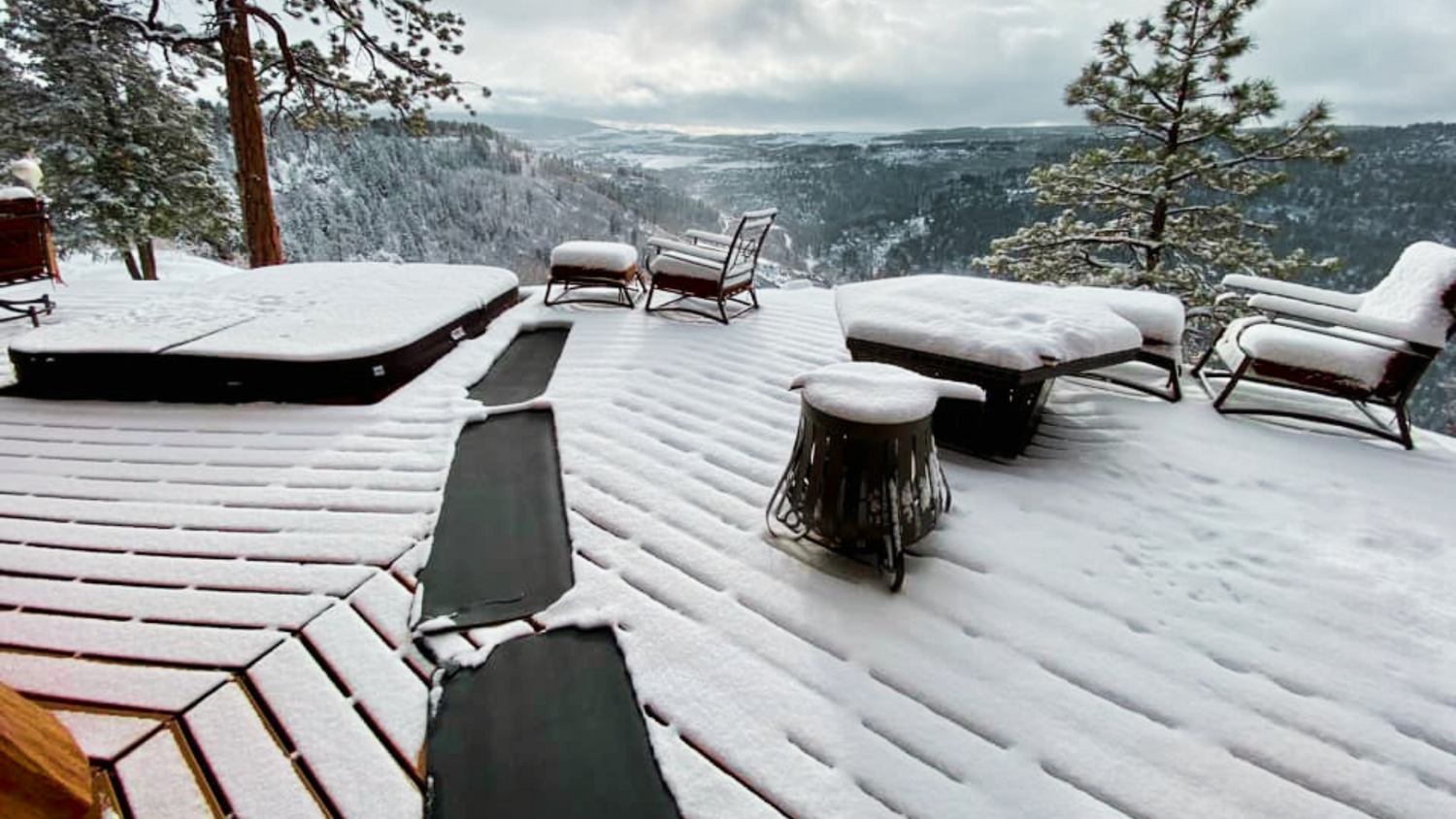 a trail of HeatTrak Snow & Ice Melting Mats is placed on a wooden, snowy deck with mountains and trees in the background