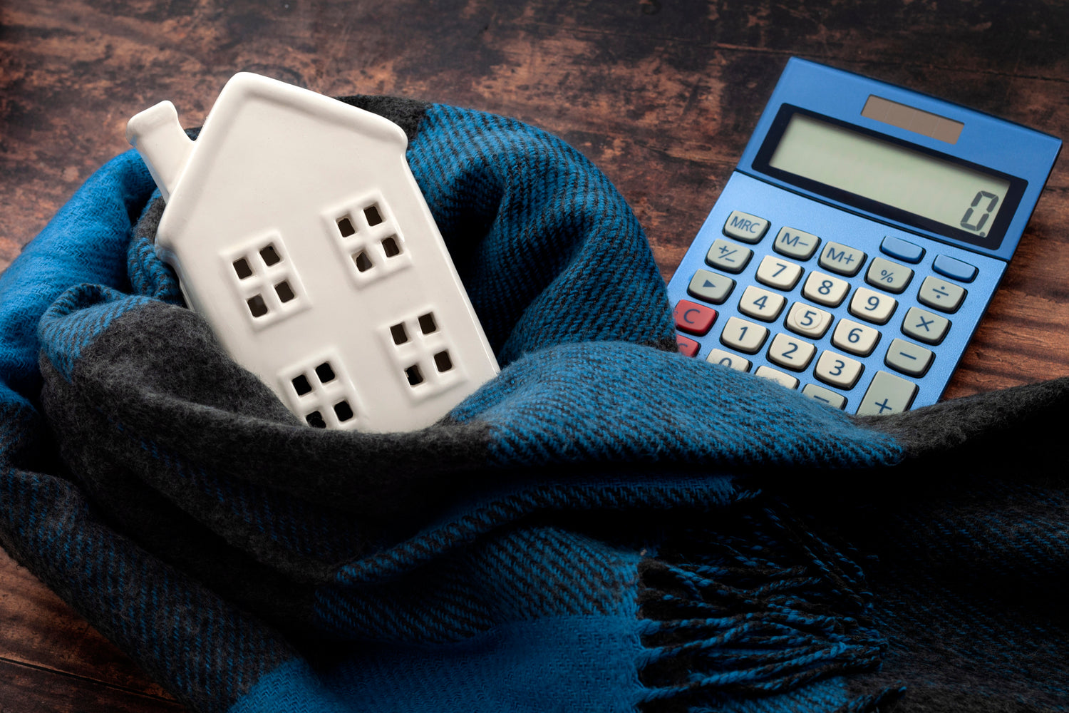 a calculator is next to a porcelain house figurine wrapped in a blue scarf