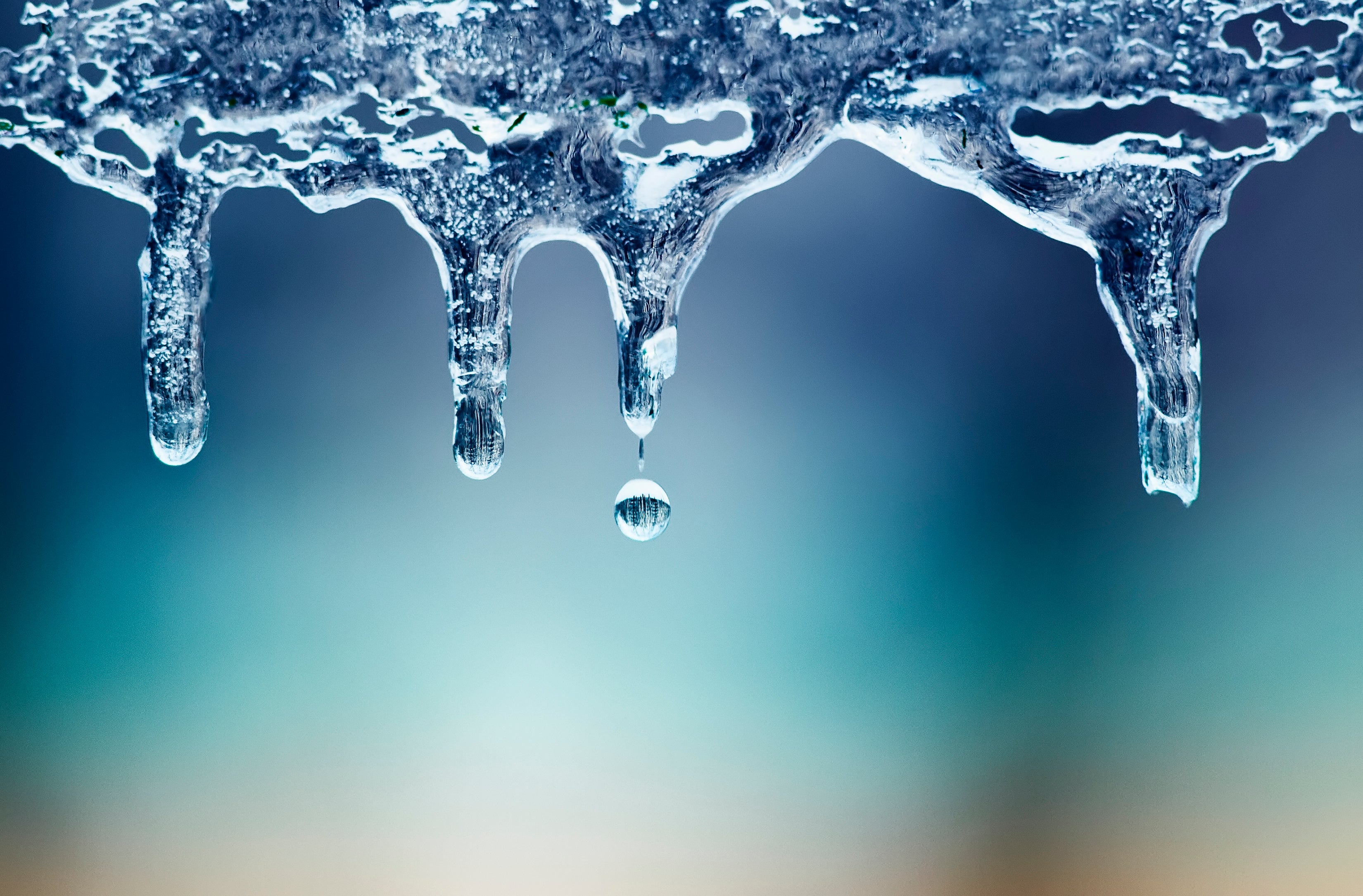 a row of icicles are shown in the forefront of a blue and yellow background
